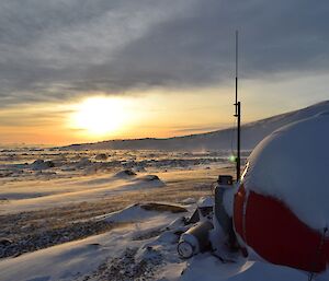 The red apple shaped hut with the repaired antenna and the sun going down in the background