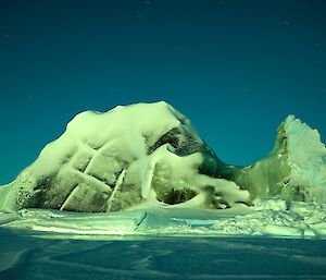A lightly snow covered jade ice berg under the moon light on a very clear night