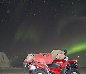 An expeditioner lying on a quad bike taking in the beauty of the night skies