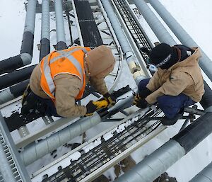 Two plumbers working on the site services domestic water line, cutting the pipe lagging with a battery operated reciprocating saw