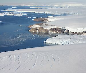 An aerial photo of glaciers and the polar ice cap where they meet with the beautiful blue ocean waters