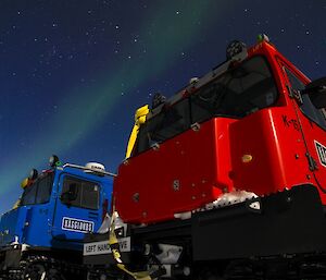 The red and blue Hägglunds parked up for the night with an aurora drifting across the clear night sky