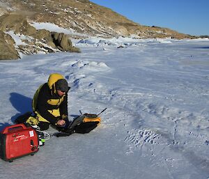 Expeditioner getting a weather update using a satellite phone, computer all powered by the small generator