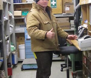 Expeditioner standing in front of the Stores computer desk giving the thumbs up