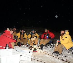 The expeditioners sitting around the Tilly light as if it was a camp fire