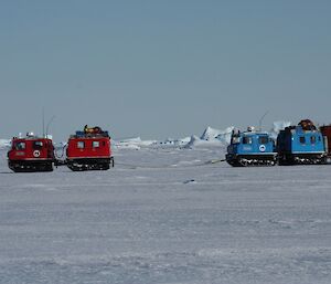 The red Hägglunds vehicle towing the blue Hagg and van on the sea ice