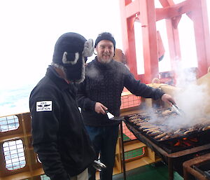 An expeditioner cooking a BBQ on the deack of the ship