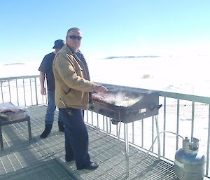 An expeditioner cooking a BBQ on the deck of the living quarters.