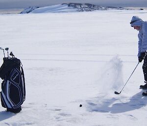 An expeditioner hitting a golf ball on an sea ice gold course