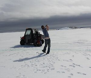 A golf player striking the golf ball on the sea ice golf course