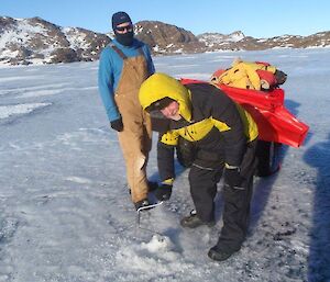 Two expeditioners drilling a metre down in the sea to test depth.