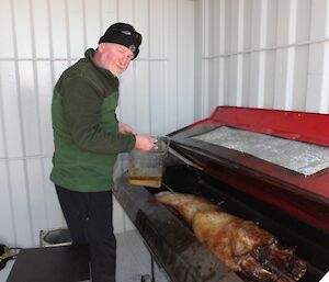 An expeditioner cooking a spit roast