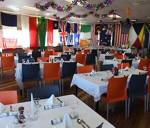 Dining room set up for dinner, the walls lines with flags from around the world