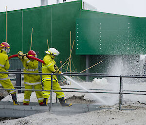 Expeditioners using a fire hose in the snow conditions