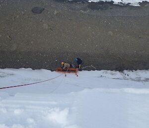 A snow cliff face with a stretcher being pulled up