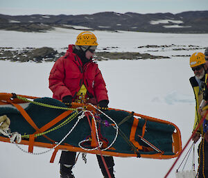 An expeditioner with a stretcher on the ice