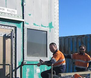 Two expeditioners getting ready to paint a building