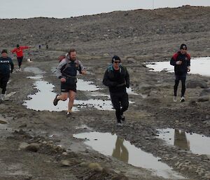 Five expeditioners running along a wet track.