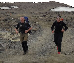 Two expeditioners with back backs on trekking along a path