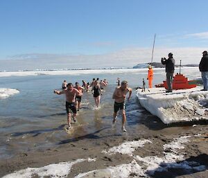 Two expeditioners running out of the sea water at davis