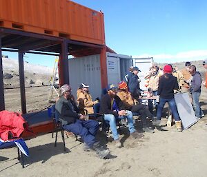 A group of expeditioners sitting near a container.