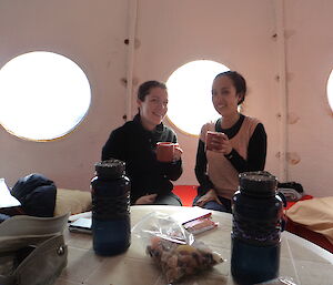 Two expeditioners in a field hut having a cuppa tea