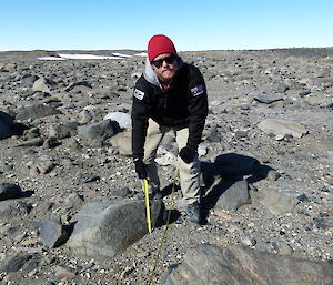 An expeditioner inspecting the size of a rock