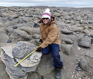 An expeditioner measuring the size of a rock