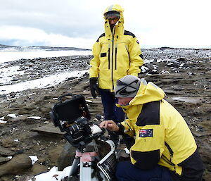 Two expditioners downloading data from a science camera in the field