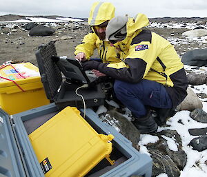 two expeditioners down loading soil data from a instrument