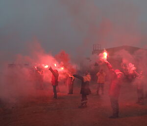 dark photo with expeditioners holding bright lit flares