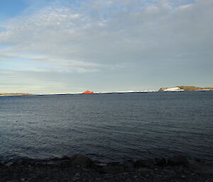 red ship in distance surrounded by icebergs