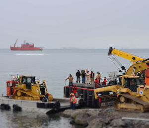 yellow dozer on a barge at the wharf ready for lifting on to shore