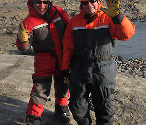 2 men standing together at the wharf waving