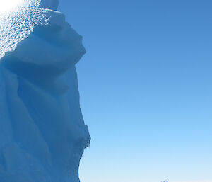 small inflatable boat alongside a very large ice berg