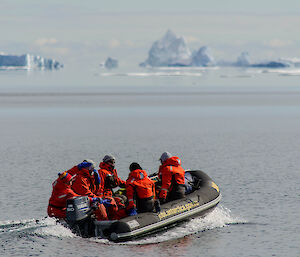 5 expeditioners in a snall inflatable boat heading out to view icebergs