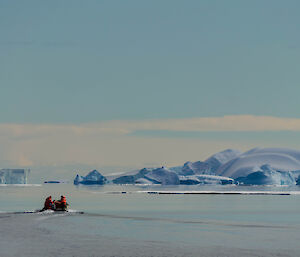 small inflatable boat heading to a cluster of icebergs