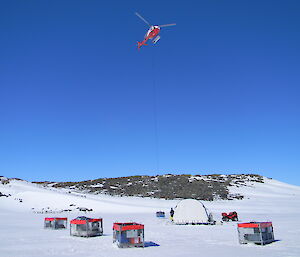 tent and cage pallets in the ice near the lake, helicopter hovering above