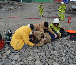 three expeditioners with a patient on their side being attended to