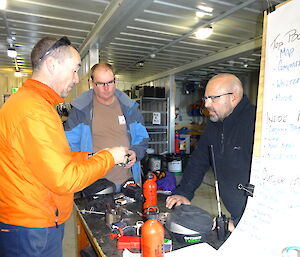 3 expeditioners arounda table checking all gear is in order