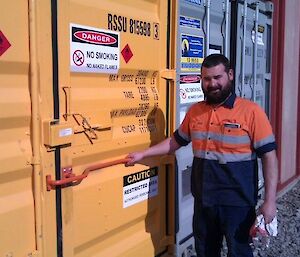 Man standing next to large shipping container holding a red handle