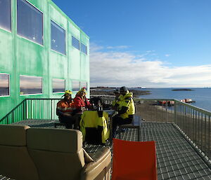 Group of expeditioners sitting around a table outside enjoying the sun