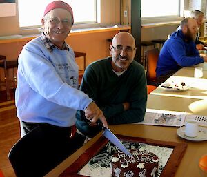 two expeditioners cutting a chocolate birthday cake