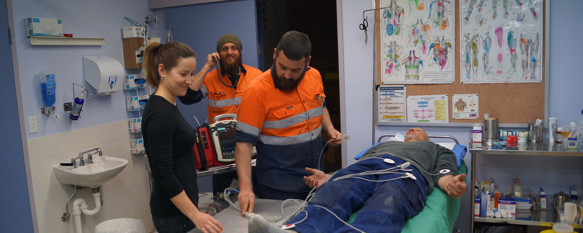 2 staff prepare a volunteer laying on the bed for medical tests