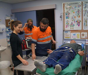 2 staff prepare a volunteer laying on the bed for medical tests