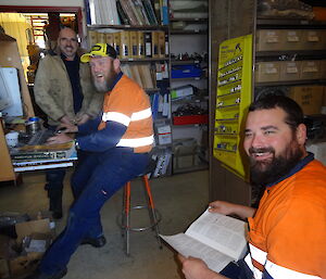 3 expeditioners standing around in the office problem solving