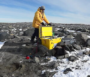 Expeditioner standing next to a large yellow box in the field