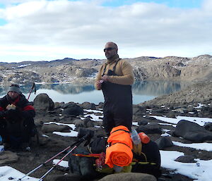 two expeditioners eating lunch with views of the lake in the background