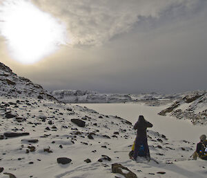 two expeditioners looking out over a frozen lake