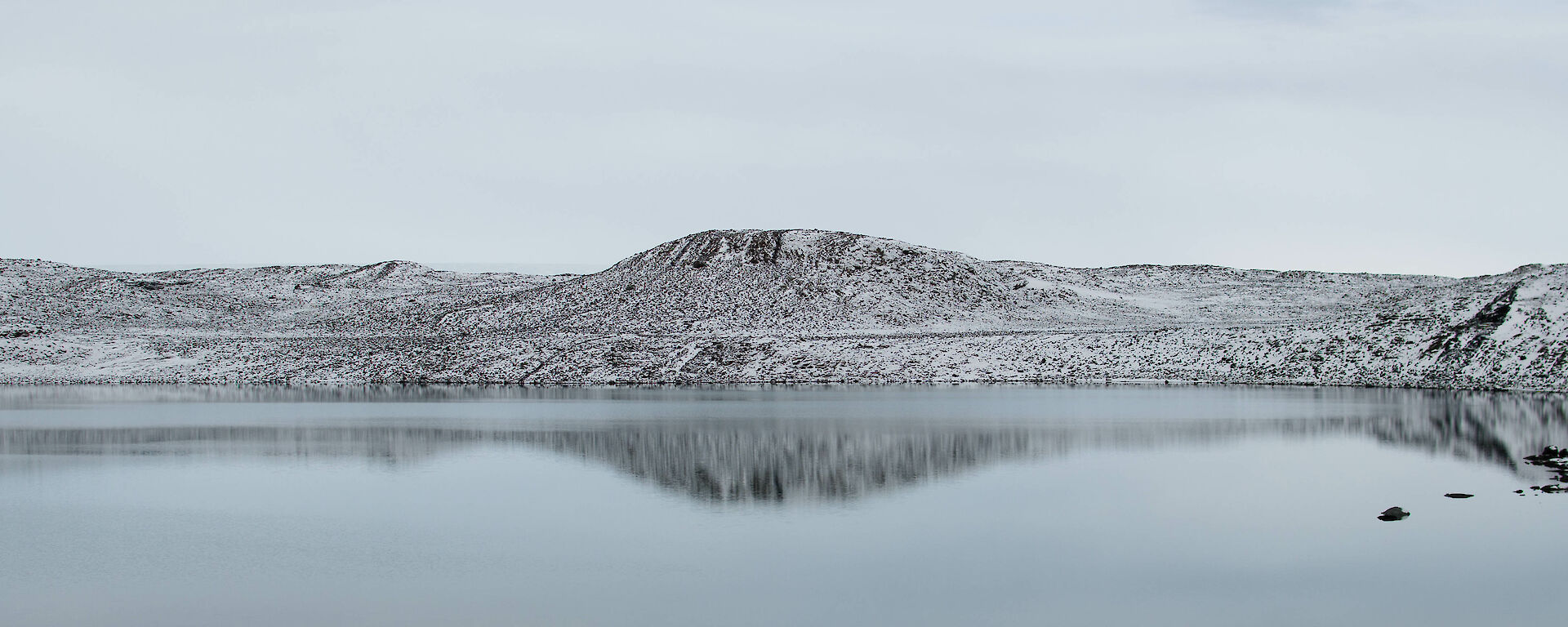 large lake showing mirror image of snow capped hills